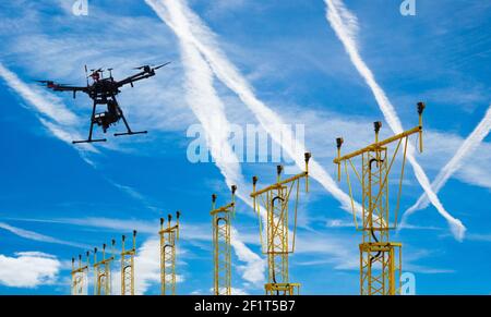 Hexacopter professional drone flying over airport runway landing lights with aircraft contrails in blue sky. Stock Photo