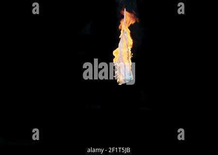 Side view of isolated Covid surgical medical mask in flames against a black background with copy space for an end of mask wearing concept Stock Photo