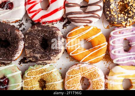 Flat lay top view image of a dozen donuts on card board box. A delicious assortment with different flavors and toppings. A vibrant colorful variety pa Stock Photo
