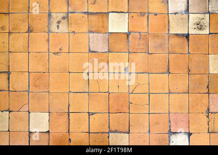Orange brown white beige old shabby worn out floor tiles with damages cracks dirt caverns potholes and paint stains. Art design background texture. Stock Photo