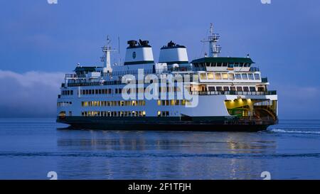 An early morning sailing for Washington State Ferries newest ferry Suquamish as it sails on calm daybreak waters during the blue hour period Stock Photo