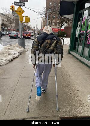 Young man with a cast on his leg gets around on crutches in Brooklyn, New York. Stock Photo