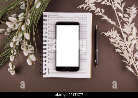 a smartphone on a notebook with a white screen and leaf decor Stock Photo