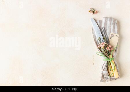 Cutlery set and beautiful pink flowers on light stone table. Easter celebration. Top view with copy space for text. Selective focus. Stock Photo