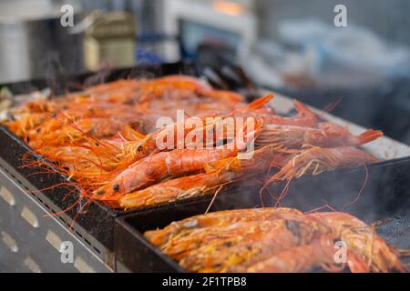 Process of cooking fresh red langoustine shrimps, prawns on grill - street food Stock Photo