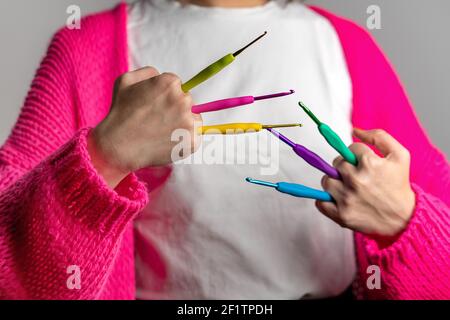 Woman with a neon pink knitted jacket holding colorful crochet needles in different sizes Stock Photo