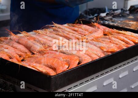Process of cooking fresh red langoustine shrimps, prawns on grill - street food Stock Photo