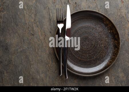 Plate, knife and fork on stone background Stock Photo