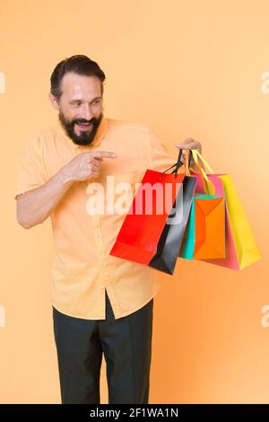 Shopping happiness. Man emotional enjoying shopping. Bearded mature man with shopping bag on yellow background. Sale and discount. Online shopping. Profitable purchase. Shop assistant or sales expert ...