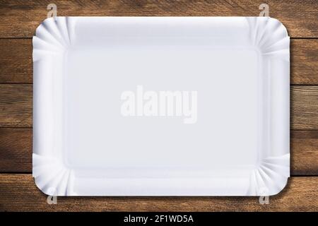 Disposable paper plate on a wooden background. Empty white cardboard plate Stock Photo