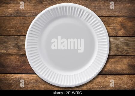 Disposable paper plate on a wooden background. Empty white cardboard plate Stock Photo