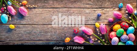 Easter Decoration - Painted Eggs In Vintage Basket On Rustic Table With Willows Branches And Tulips Stock Photo