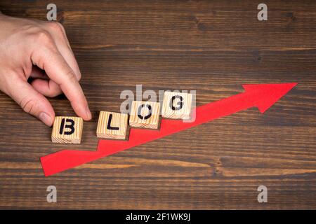 BLOG, business concept. Red arrow indicates the development and growth. Steps, wooden background. Stock Photo