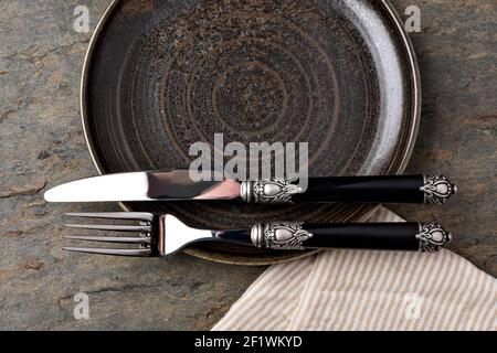Plate, knife and fork on stone background Stock Photo