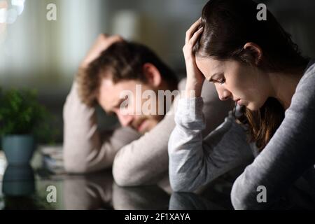 Sad couple complaining after argument in the night at home Stock Photo