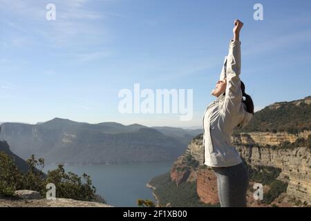 Happy trekker raising arms celebrating success in the top of a cliff in the mountain Stock Photo