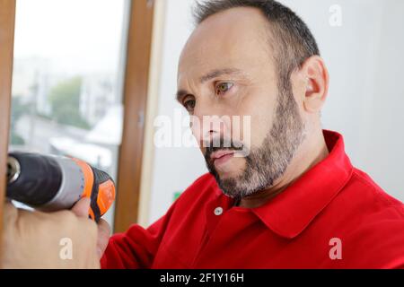 a bearded man using a drill Stock Photo