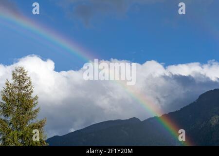 Rainbow in mountain landscape with blue sky and white clouds Stock Photo