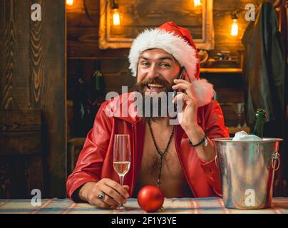 Happy Santa man posing with phone. Modern santa claus in red clothes. Surprised bearded guy using smart phone. Happy christmas. Stock Photo