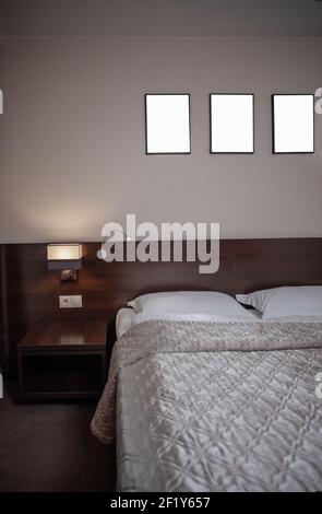 Interior of a comfortable hotel bedroom in the morning in luxury style. Big window. Black wooden photo frames mockup, interior decor Stock Photo