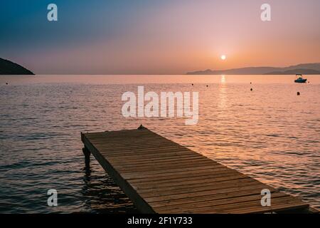 Sunrise, wooden pier at the beach in sunrise time with golden sky. Vacation and travel concept. Crete Greece Stock Photo