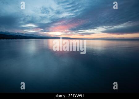 Sunset from the beach of the popular resort town of Kadji Say in Kyrgyzstan's Issyk Kol oblast on the southern shore of Issyk Kol lake. Stock Photo