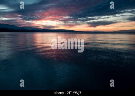 Sunset from the beach of the popular resort town of Kadji Say in Kyrgyzstan's Issyk Kol oblast on the southern shore of Issyk Kol lake. Stock Photo