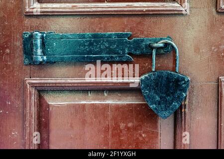 Black padlock closure on a mahogany wood door Stock Photo