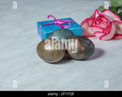 Painted for Easter egg, box with gift and bouquet of roses lie on gray table. Selective focus Stock Photo