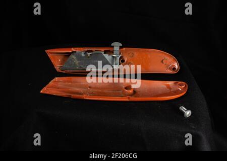 orange utility knife opened and isolated on a black background Stock Photo