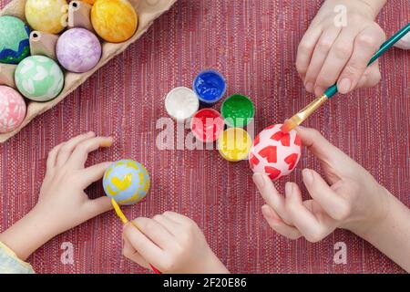 Cropped view of mother and son painting Easter egg together. Easter craft. Preparing decorations for Easter, creativity with children, traditional sym Stock Photo