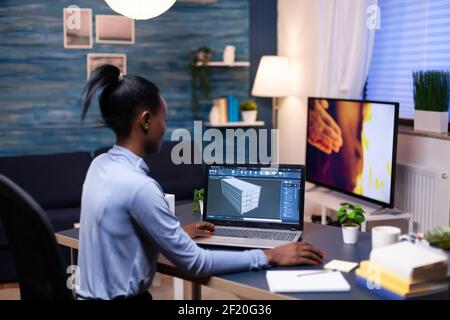African entrepreneur developer working from home office late at night. Industrial black female engineer studying prototype idea on personal computer showing software on device display Stock Photo