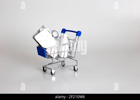 White and silver blisters of pills and drops in a supermarket trolley on a white background Stock Photo