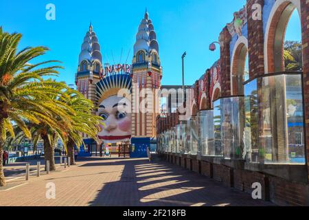 The smiling face entrance to Luna Park Sydney, an amusement park. To the right is the decorative wall of the North Sydney Olympic Pool Stock Photo