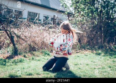 little girl with long blond hair holding white fluffy rabbit Stock Photo