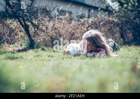 little girl with white rabbit pet playing in the garden Stock Photo