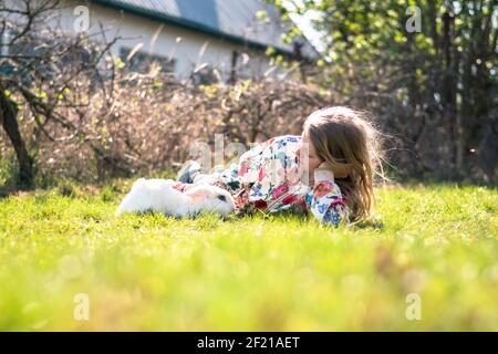 little girl with white rabbit pet playing in the garden Stock Photo