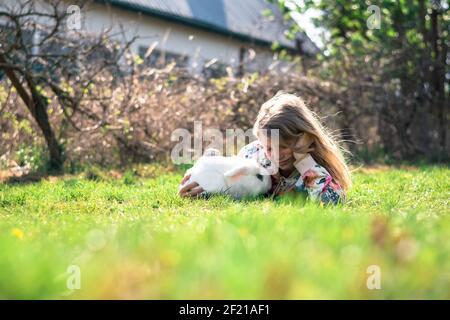 little girl with white rabbit pet playing in the garden Stock Photo