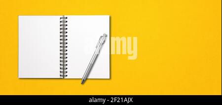 Blank open spiral notebook and pen isolated on yellow banner Stock Photo