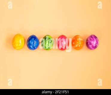 Colorful Easter eggs homemade painted top view flatlay on pastel orange peach background bright fresh design, Happy Easter, spring concept Stock Photo