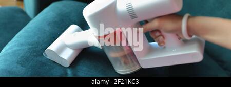 Use small vacuum cleaner to clean fabric on sofa. Stock Photo