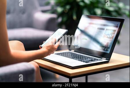 Wireless wifi for remote work in airport lounge bar, hotel lobby or cafe. Phone and laptop. Woman using smartphone and modern notebook pc computer. Stock Photo