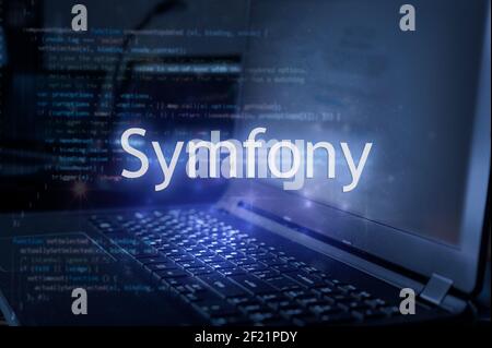 Symfony inscription against laptop and code background. Framework for web development. Stock Photo