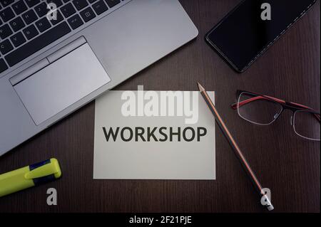 Workshop concept. Top view of laptop, phone, glasses and pencil with card with inscription workshop. Stock Photo