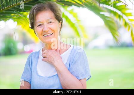 Smiling middle aged mature grey haired woman looking at camera, happy old lady in glasses posing park outdoor, positive single senior retired female s Stock Photo