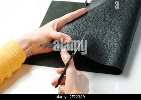 Tailor hands cut piece of leather macro close up view Stock Photo