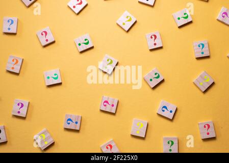 Colorful question mark symbol on wooden tile agains yellow background. Concept of Diversity, FAQ, Q and A and questions Stock Photo