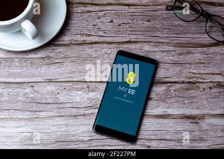 A mobile phone or cell phone laid on a wooden table or desk with the My EE app open Stock Photo