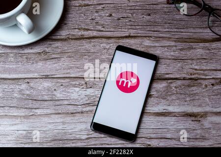 A mobile phone or cell phone laid on a wooden table or desk with the Match dating app open Stock Photo