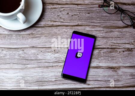 A mobile phone or cell phone laid on a wooden table or desk with the Twitch streaming app open Stock Photo